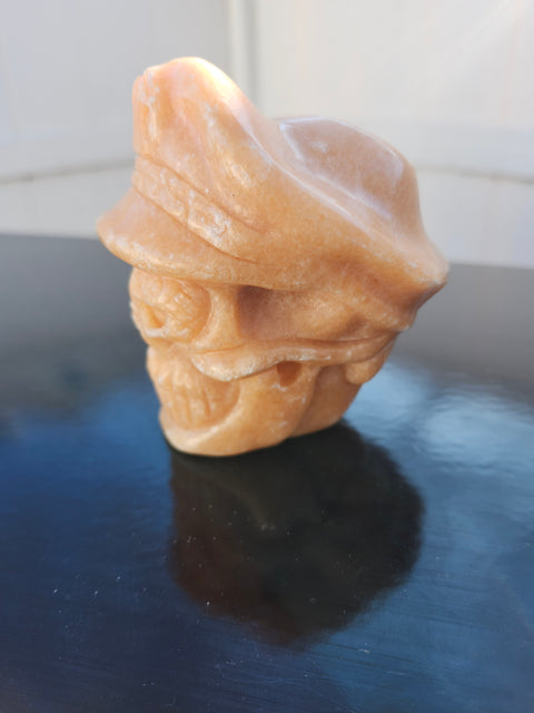 Orange calcite skull with a hat