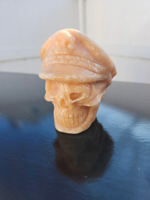 Orange calcite skull with a hat