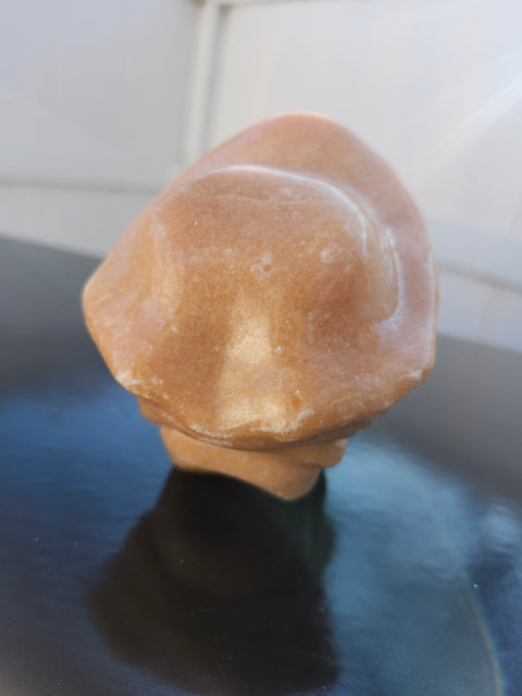 Orange calcite skull with a hat