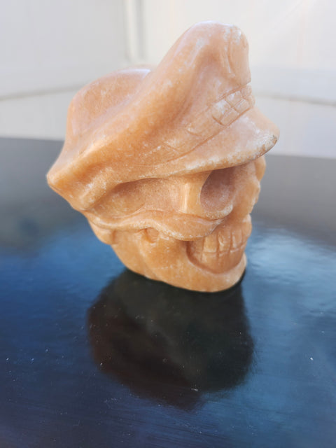 Orange calcite skull with a hat